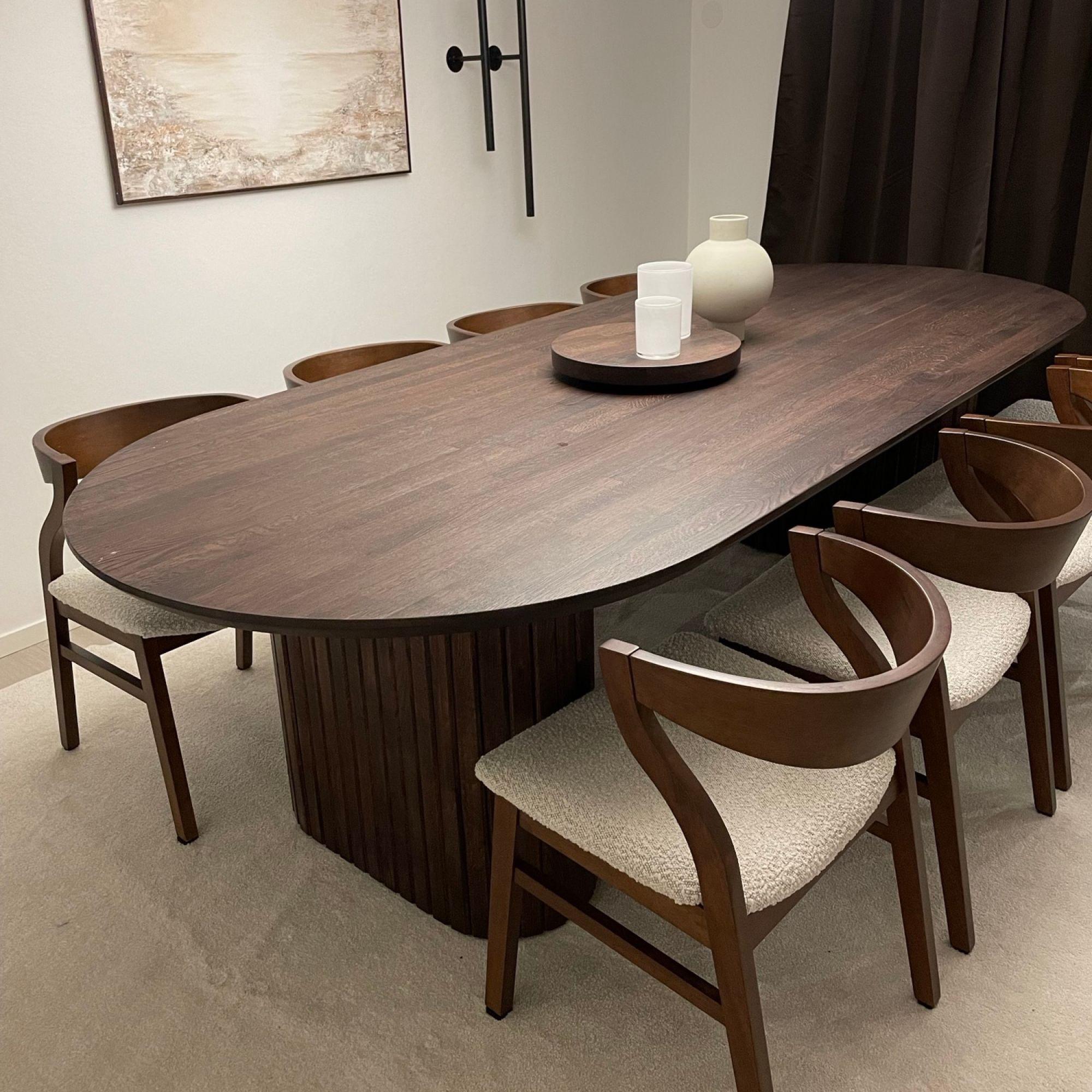 Ovalt matbord i brun färg och bruna stolar