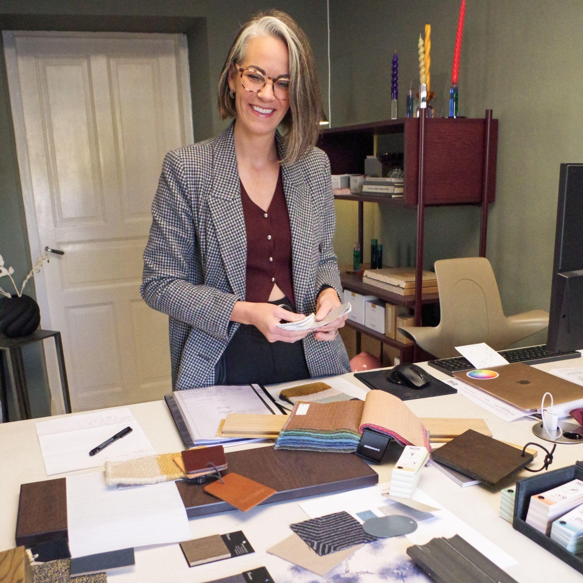 Marie Rasmussen på Interior by Mastvikens kontor. Bordet är fyllt med prover i olika material.