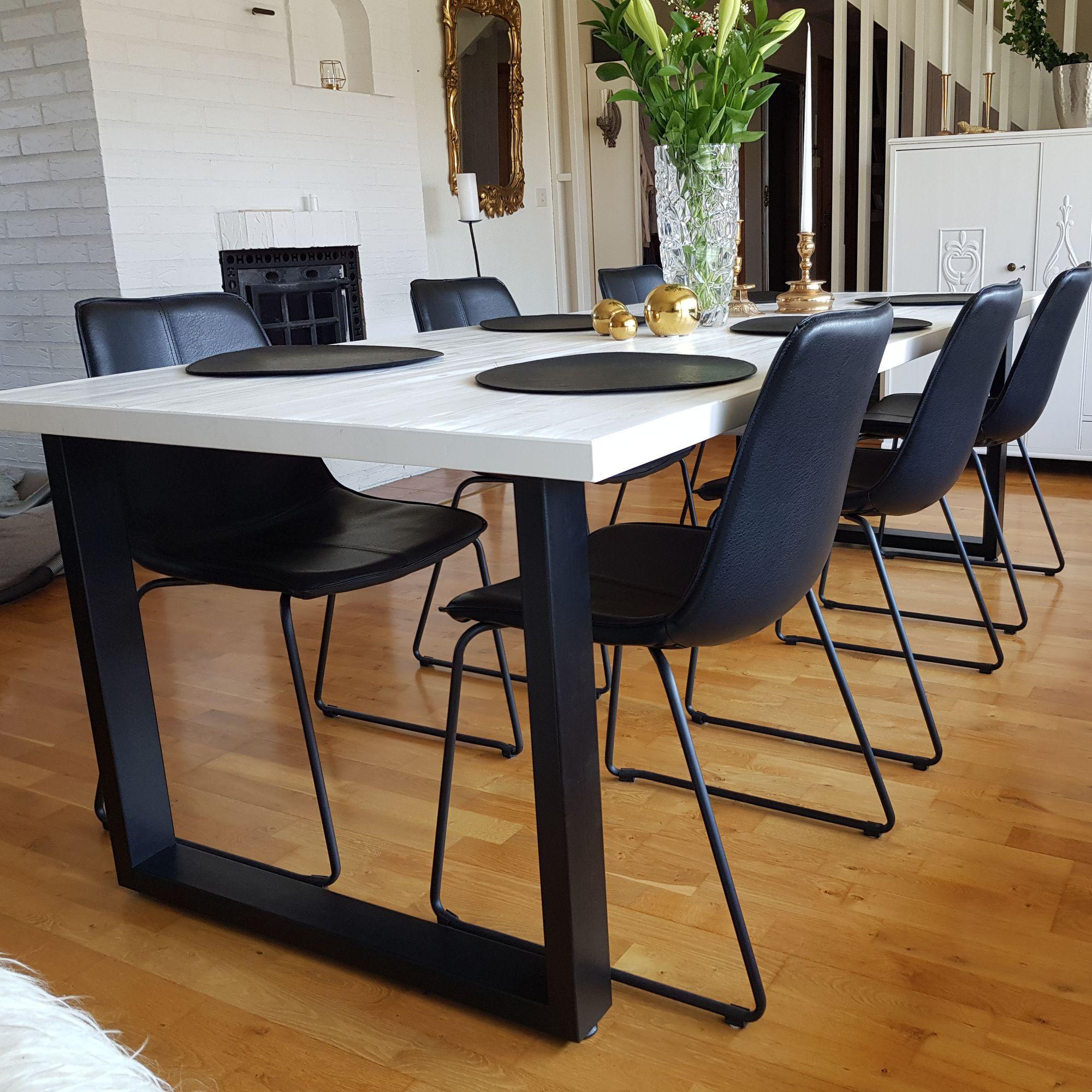Vitt bord med svarta stålben och svarta stolar i ett vardagsrum
