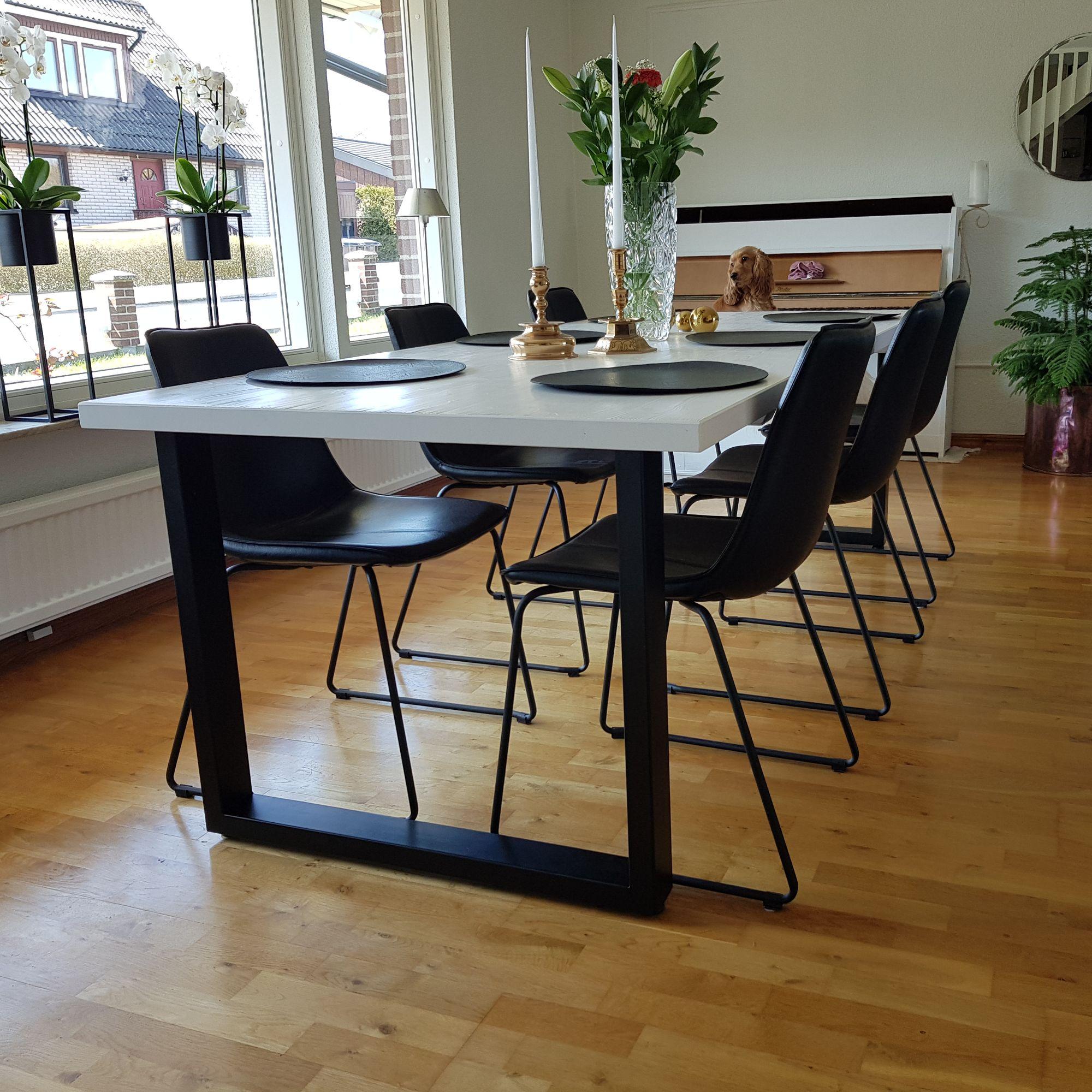 Vitt bord med svarta stålben och svarta stolar i ett vardagsrum